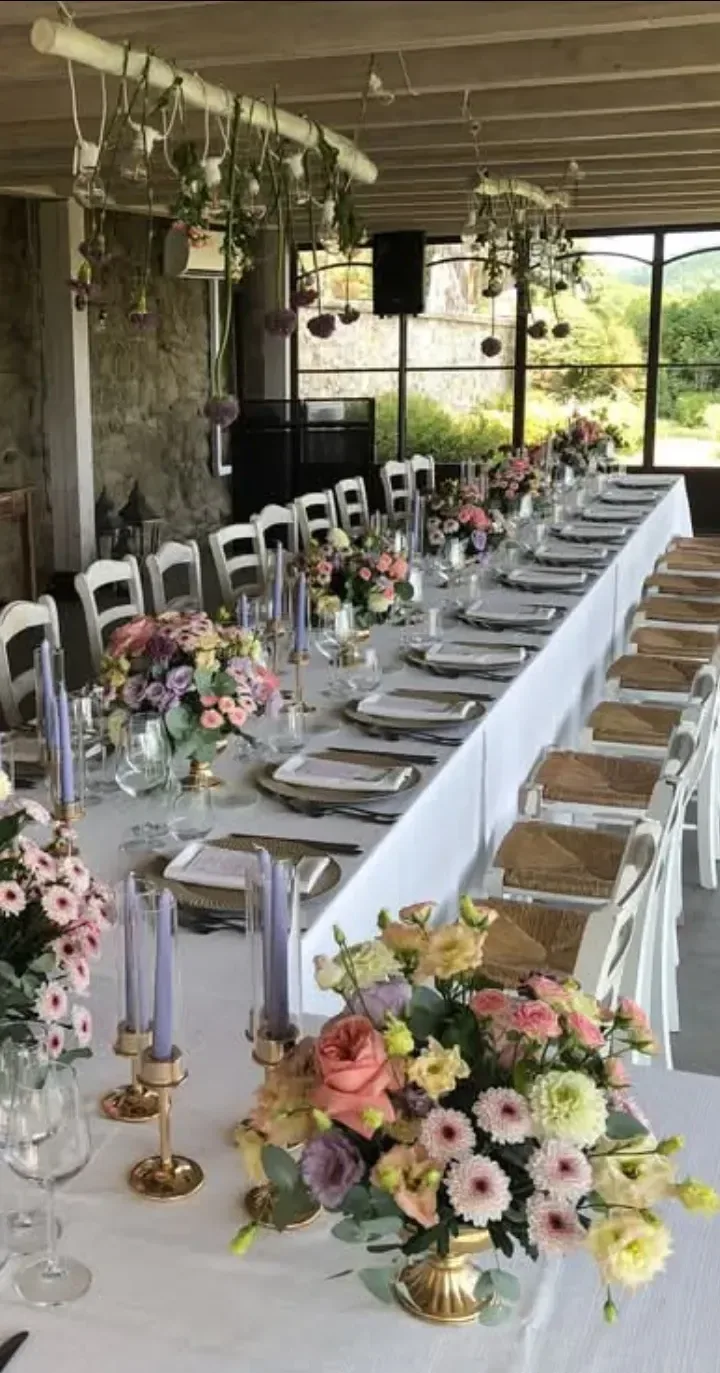 Tavolo imperiale allestito con fascia di fiori pastello, candele lilla su candelieri dorati e composizioni sospese sopra i commensali